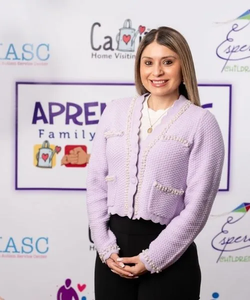 Ali Covarrubias-Parra posing in front of an Aprendamos Family of Services backdrop