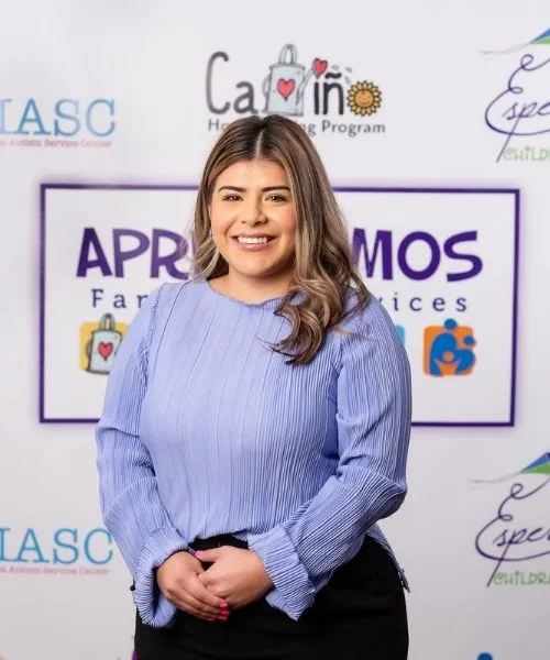 Cinthia Herrera posing in front of an Aprendamos Family of Services backdrop