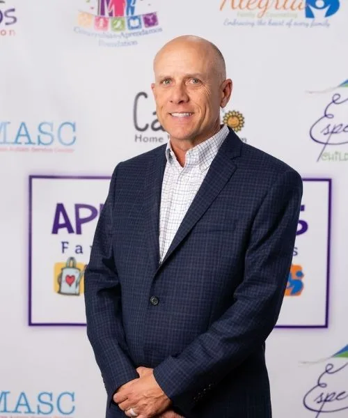 Danny Palma posing in front of an Aprendamos Family of Services backdrop