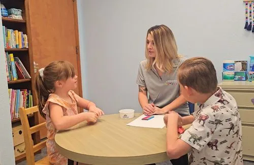 Counselor in an office setting in therapy with two children