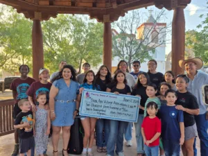 Group of children and adults presenting a $2,300 donation to the Dona Ana Village Association Youth Development Program.